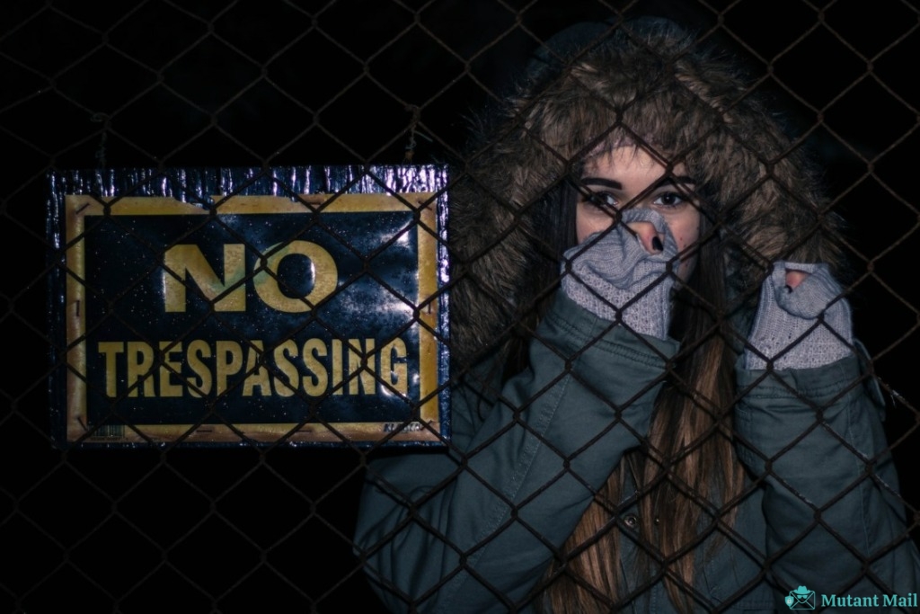 Woman Behind Black Chainlink Fence With No Trespassing Signage