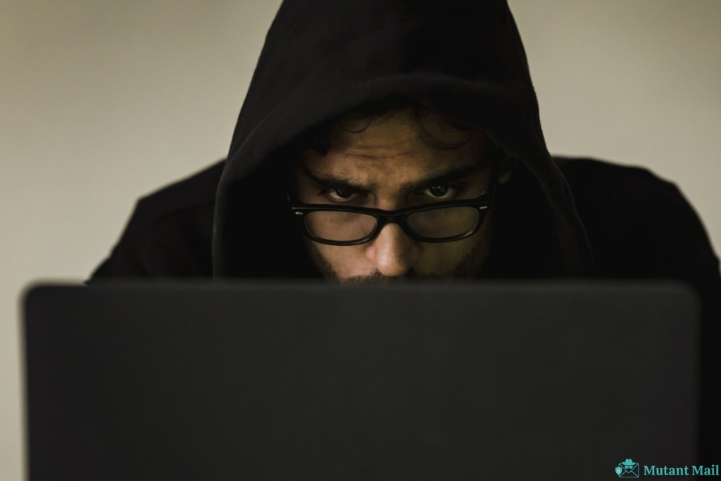 Serious young male programmer wearing black hoodie browsing netbook and hacking software in studio