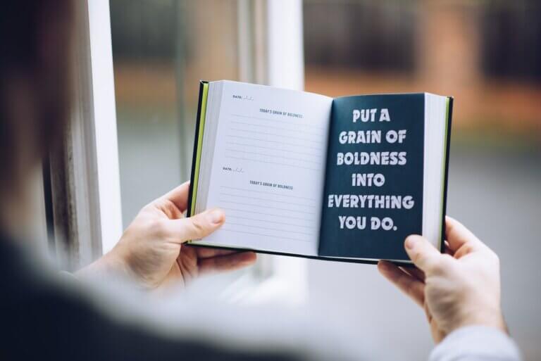 Faceless man demonstrating message in open notebook at home