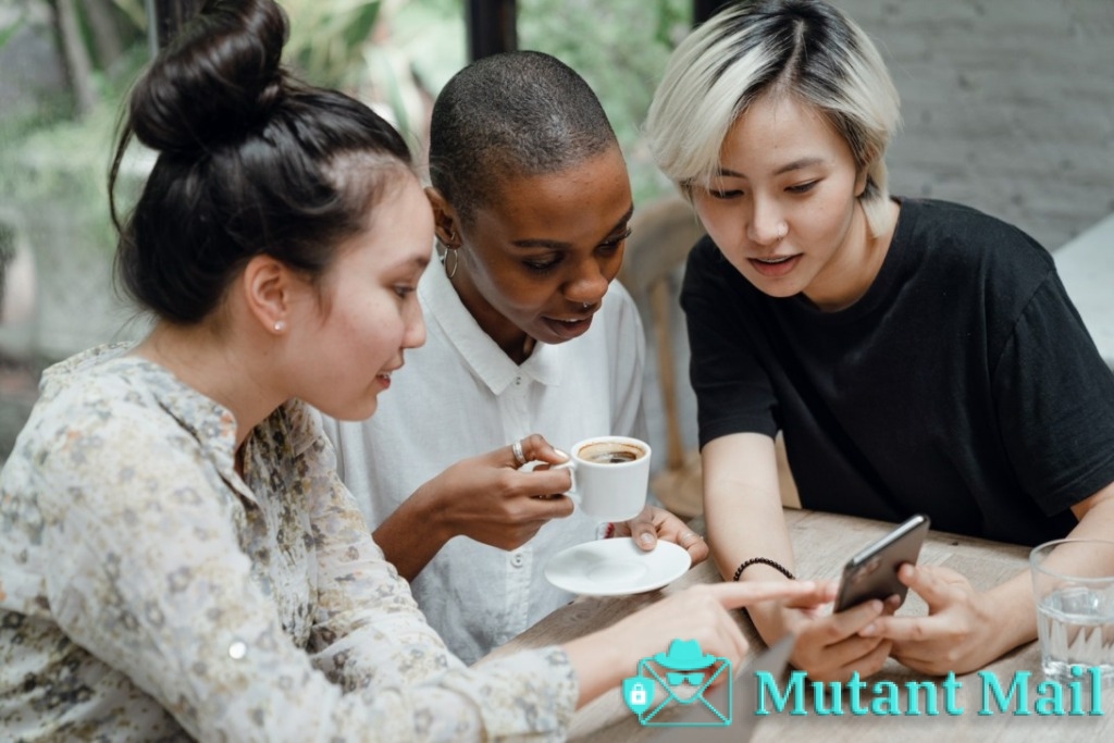 Diverse female friends checking social media on mobile in cafe