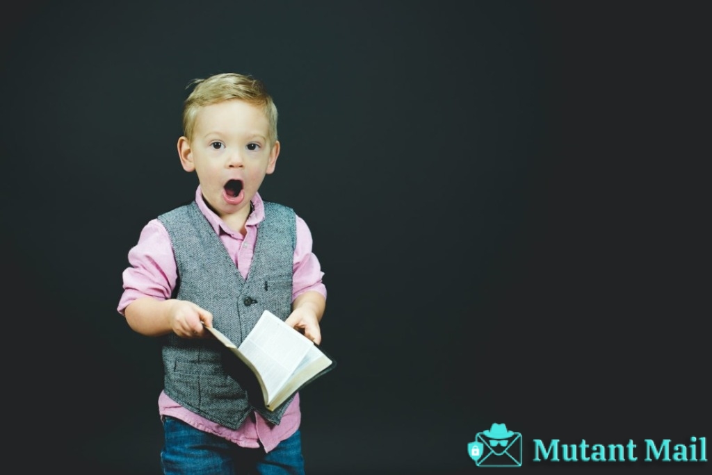 boy wearing gray vest and pink dress shirt holding book