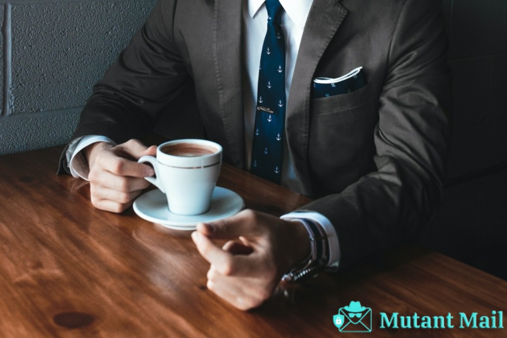 man holding cup filled with coffee on table