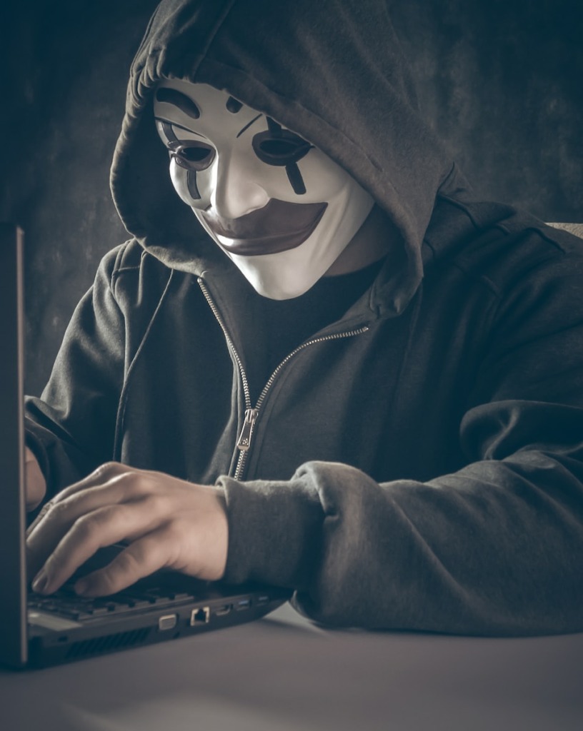 a person wearing a mask using a laptop